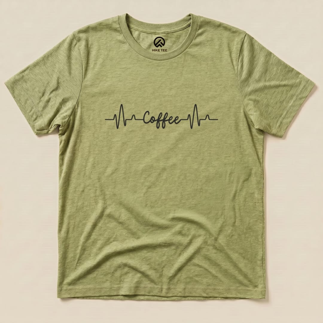 A green graphic t-shirt featuring a heartbeat line with the word "Coffee" in a stylish font, part of the Heart Beat Coffee Shirt collection.