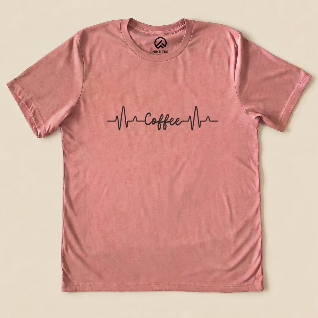 A pink graphic t-shirt featuring the slogan "Coffee" with heartbeat lines, labeled as the Heart Beat Coffee Shirt.