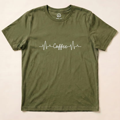 A graphic t-shirt in olive green featuring a heartbeat line design with the word "Coffee" printed across the chest, labeled as "Heart Beat Coffee Shirt.