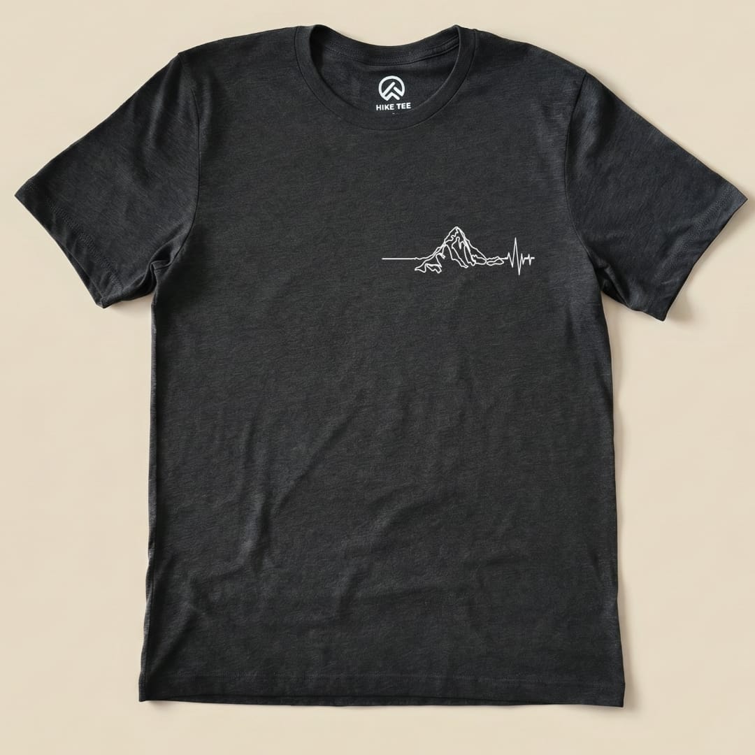 A flat lay of the Heart Rate Mountain Shirt features a minimalistic white mountain graphic with a heartbeat line design.