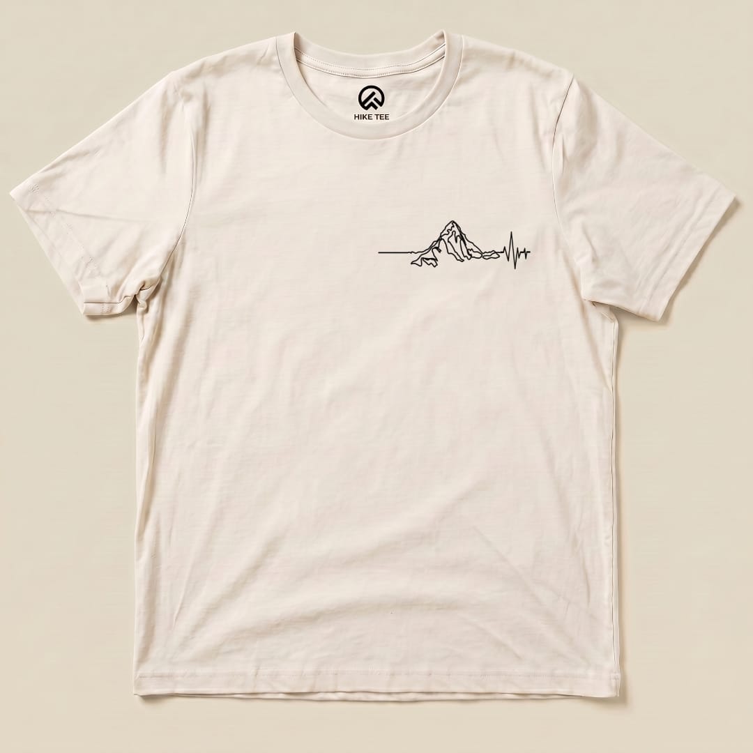 A cream-colored graphic t-shirt featuring a minimalist mountain design and heartbeat line, labeled as "Heart Rate Mountain Shirt.