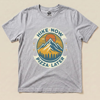 Gray graphic t-shirt featuring mountains and the slogan "Hike Now Pizza Later," perfect for outdoor enthusiasts.