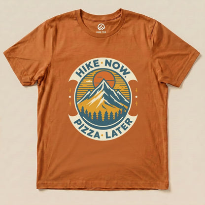 Graphic t-shirt featuring a mountain design with the slogan "Hike Now Pizza Later" on an orange background.