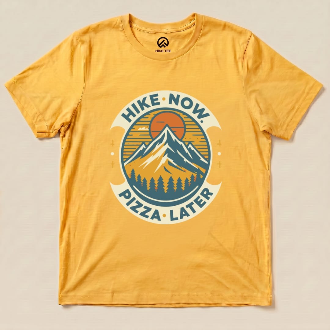 Graphic t-shirt featuring the slogan "Hike Now Pizza Later" with a mountain and sunset design on a vibrant yellow background.