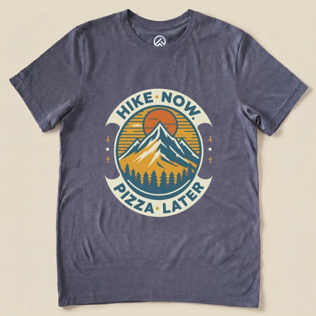 Graphic t-shirt featuring a mountain design with the slogan "Hike Now Pizza Later Shirt - del" in a circular emblem.