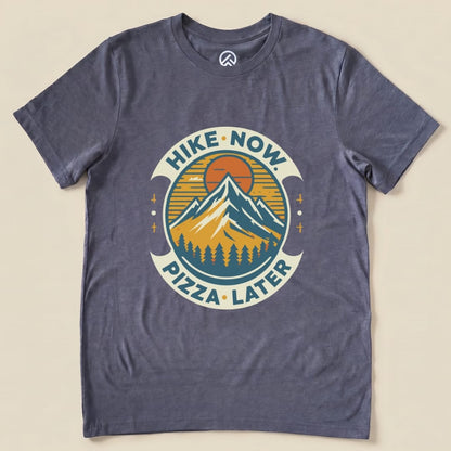 Graphic t-shirt featuring a mountain design with the slogan "Hike Now Pizza Later Shirt - del" in a circular emblem.