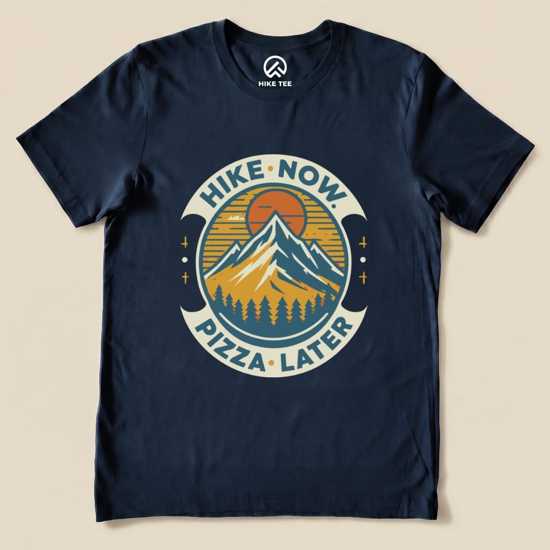 Navy graphic t-shirt featuring a mountain design with the slogan "Hike Now Pizza Later Shirt - del" in a circular layout.
