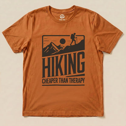 The graphic t-shirt features the slogan "HIKING CHEAPER THAN THERAPY" alongside an illustration of a hiker and mountains.