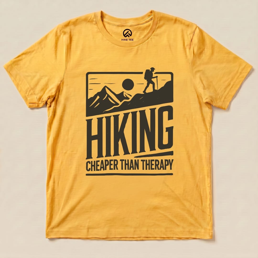 A yellow graphic t-shirt features the slogan "Hiking Cheaper Than Therapy" alongside a hiker silhouetted against mountains and a sun.