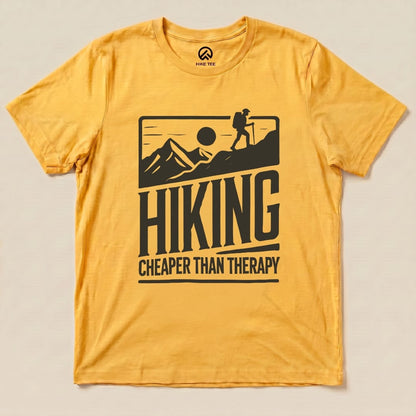 A yellow graphic t-shirt features the slogan "Hiking Cheaper Than Therapy" alongside a hiker silhouetted against mountains and a sun.