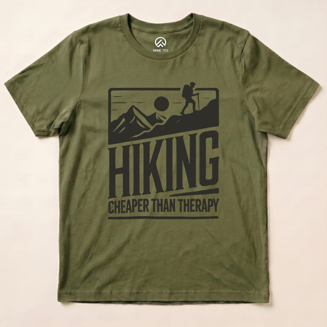 The olive green graphic t-shirt features the slogan "Hiking Cheaper Than Therapy" with a hiker and mountains design.