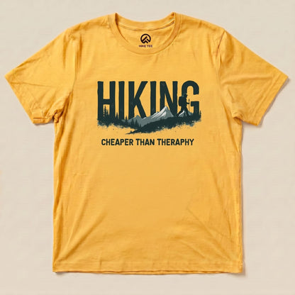 A yellow graphic t-shirt featuring the text "HIKING - Cheaper than Therapy" alongside a mountain and forest silhouette.