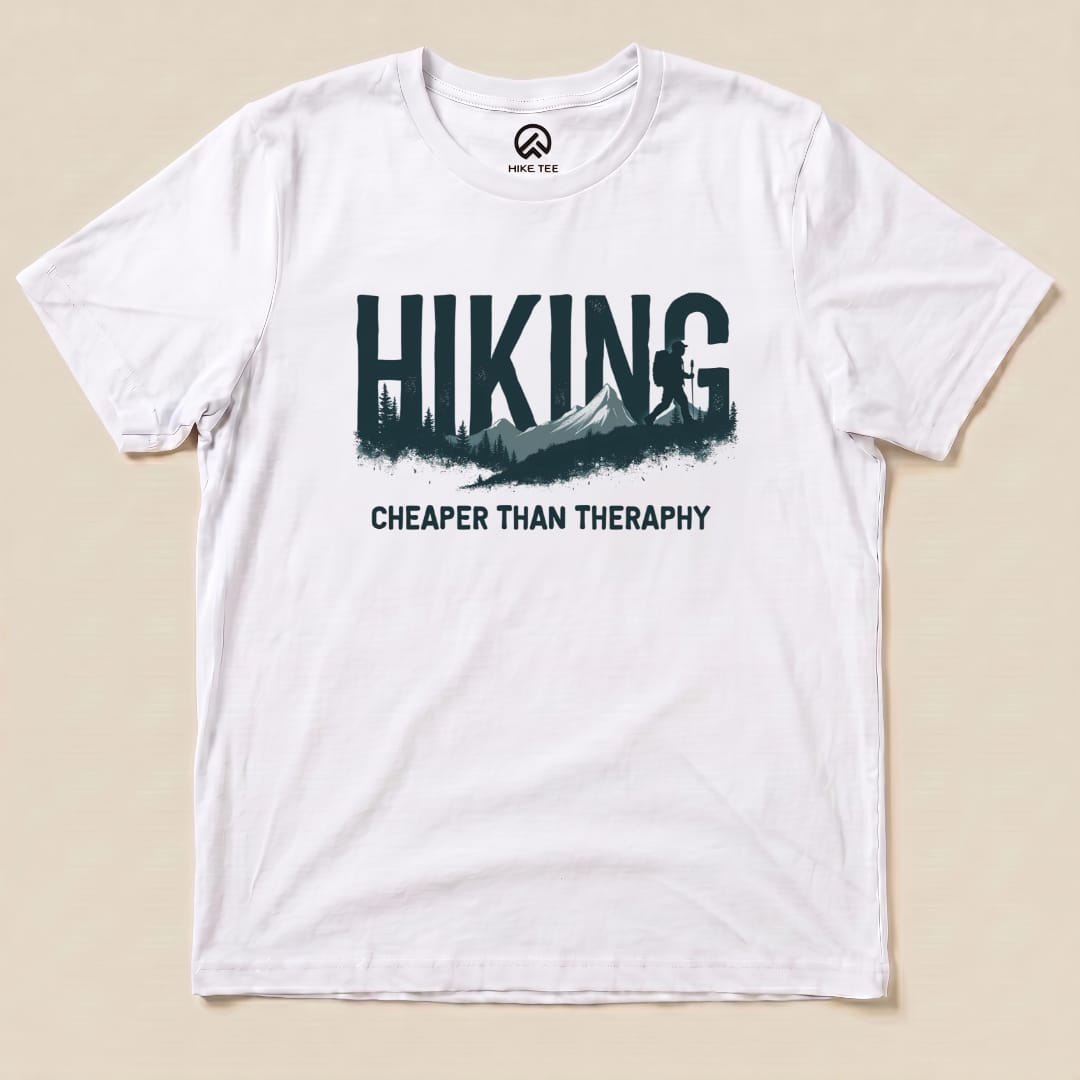 Graphic t-shirt from Hike Tee featuring the phrase "Hiking - Cheaper than Therapy" with a mountain and tree design.