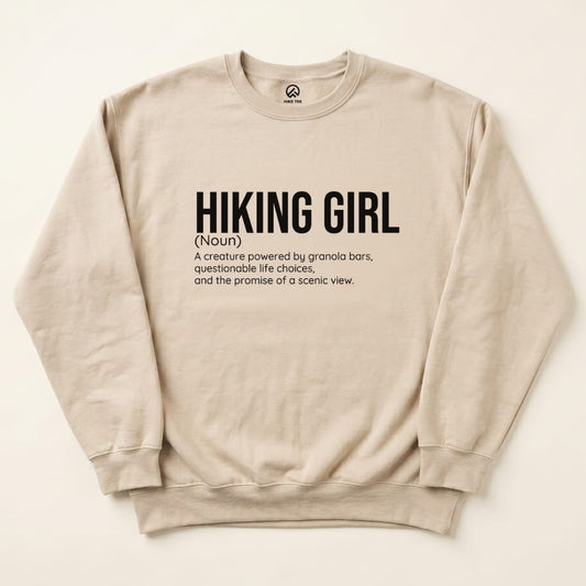 A beige "Hiking Girl Definition Sweatshirt" featuring humorous text defining a hiking girl and her traits.
