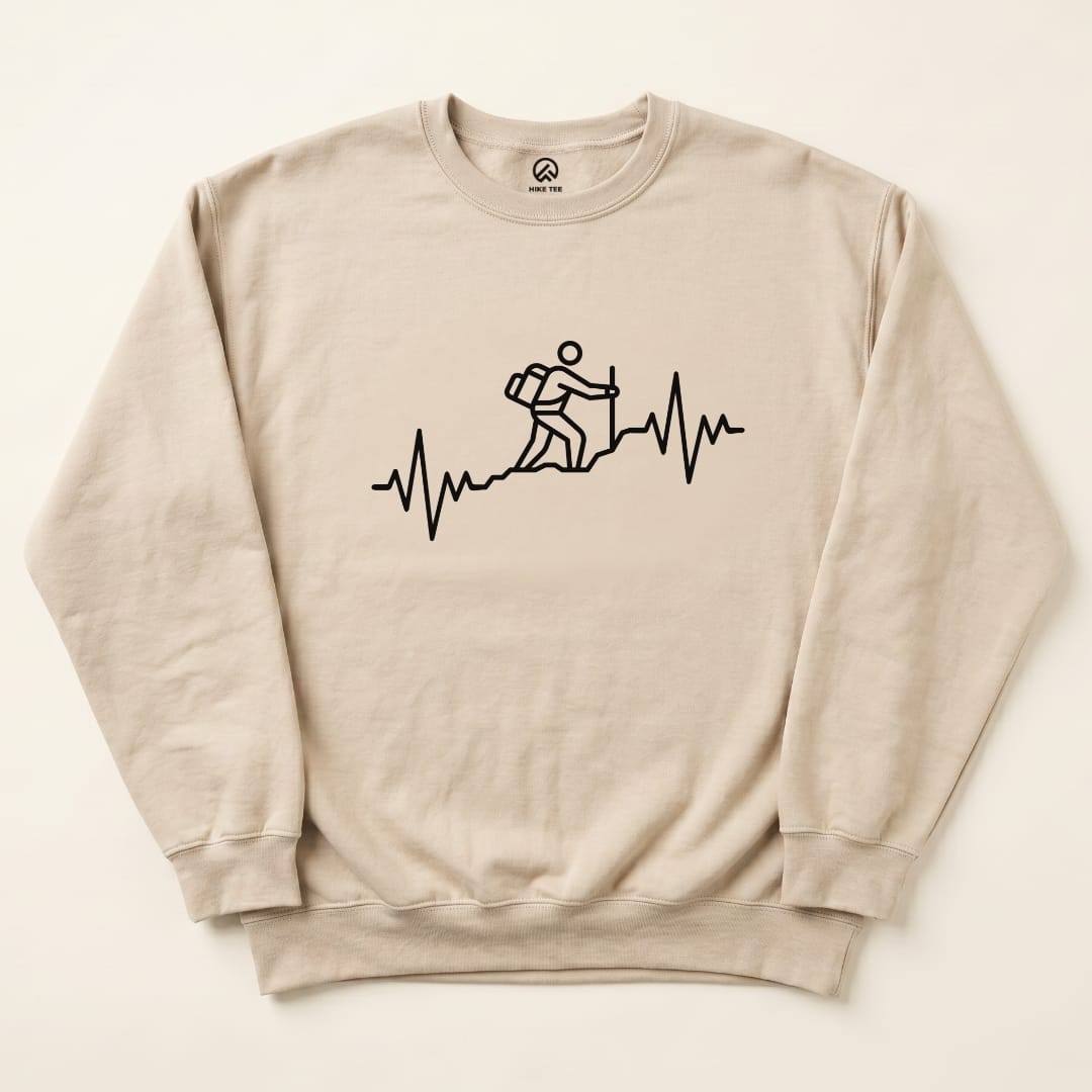 A beige "Hiking Heart Rate Sweatshirt" featuring a graphic of a hiker ascending a trail with a heartbeat line below.