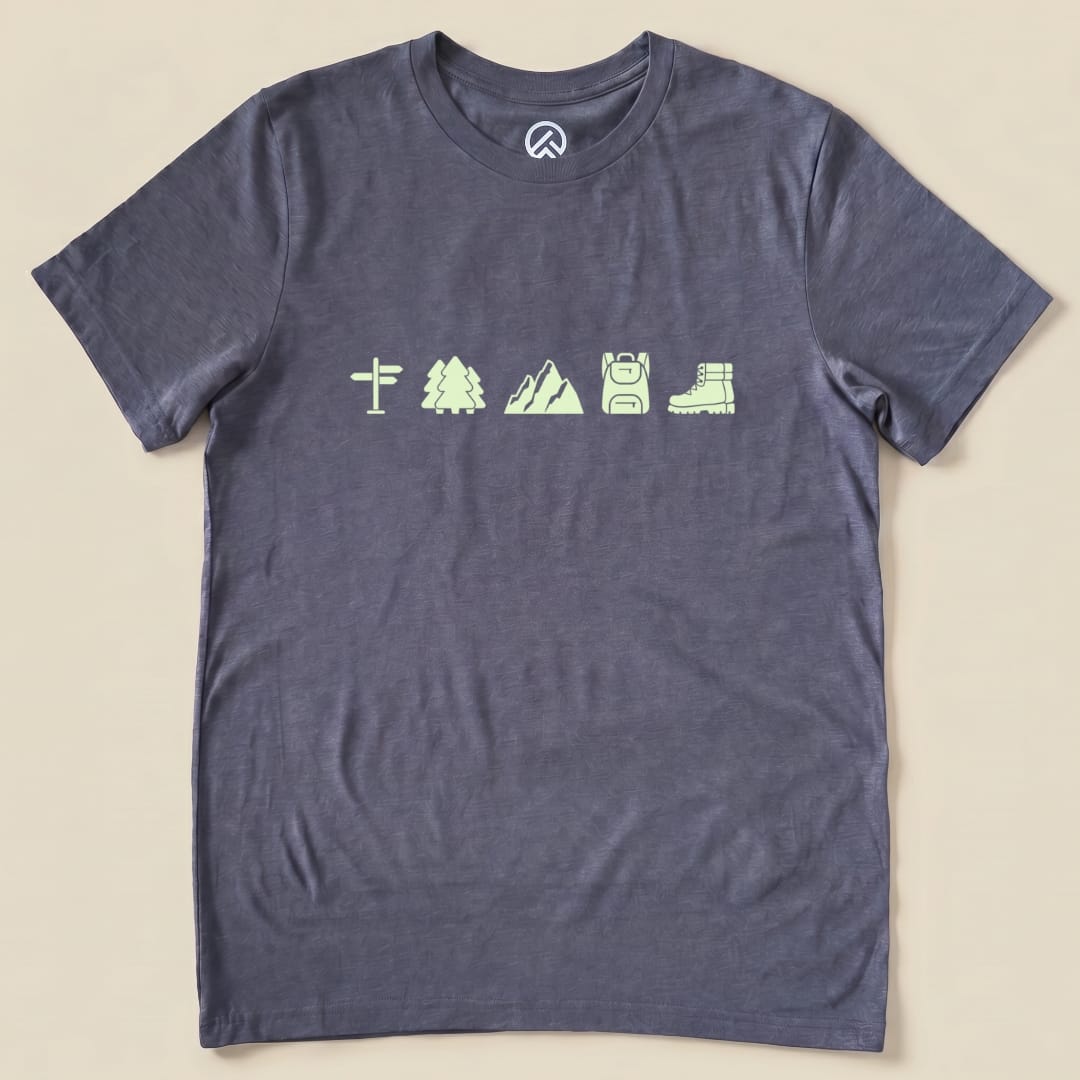 The Hiking Mini Shirt is a graphic t-shirt in dark gray featuring glowing icons of a signpost, trees, mountains, a backpack, and hiking boots.