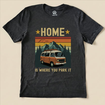 A graphic t-shirt featuring the phrase "HOME IS WHERE YOU PARK IT" above an illustration of a vintage camper van and mountains.
