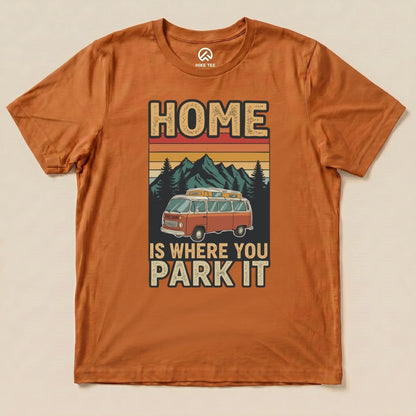 The orange graphic t-shirt features a retro design with the phrase "HOME IS WHERE YOU PARK IT" and an illustration of a vintage camper van against a mountain backdrop.