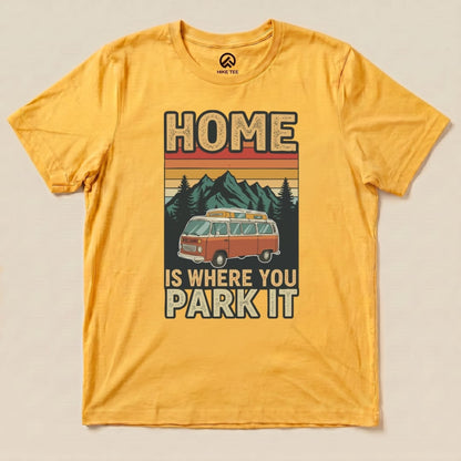 A graphic t-shirt in vibrant yellow featuring a retro van and the slogan "HOME IS WHERE YOU PARK IT" against mountains.
