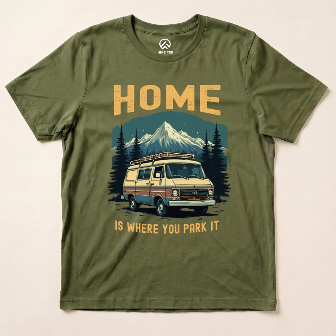 Graphic t-shirt featuring the phrase "HOME IS WHERE YOU PARK IT" above an illustrated camper van and mountain scene.