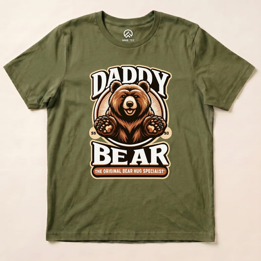A graphic t-shirt featuring a friendly bear with the text "Daddy Bear" and "The Original Bear Hug Specialist," in earthy tones.