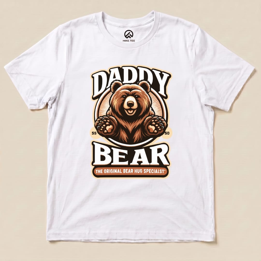 White graphic t-shirt featuring a bear illustration with the text "Daddy Bear" and "The Original Bear Hug Specialist" below.