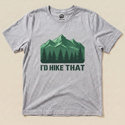 A graphic t-shirt featuring the slogan "I'D HIKE THAT" above a mountain and pine tree design on a gray background.