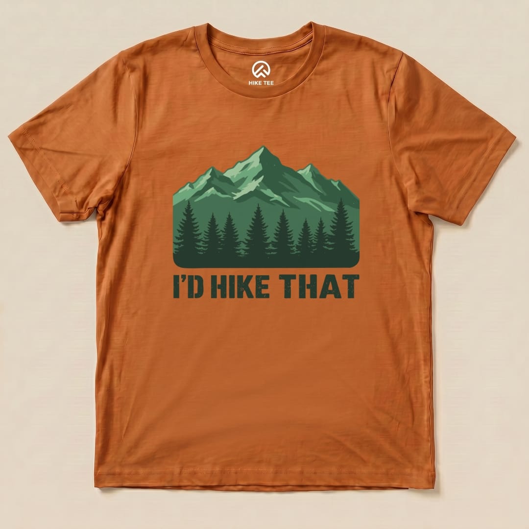 Graphic t-shirt in orange featuring a green mountain design with the text "I'D HIKE THAT" prominently displayed below.