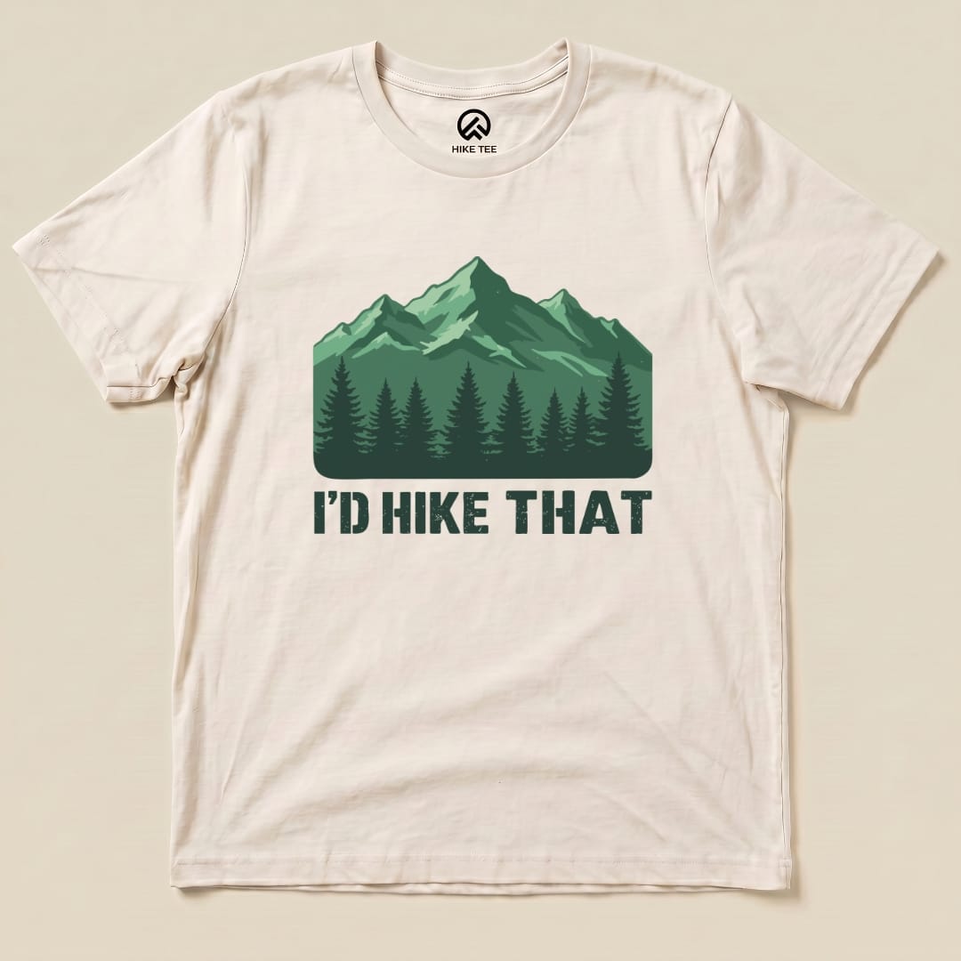 A cream graphic t-shirt features a green mountain design with the slogan "I'D HIKE THAT" printed below a tree line.