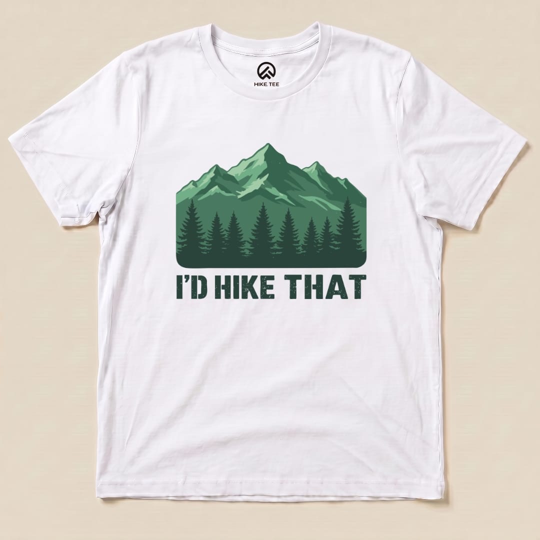 A white graphic t-shirt featuring a mountain landscape and the slogan "I'D HIKE THAT" in bold letters below.