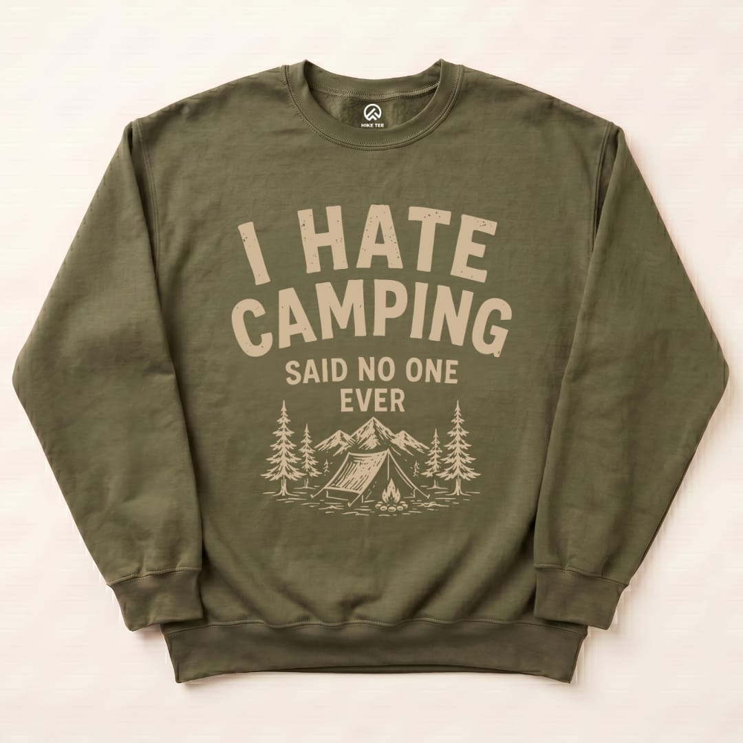 An olive-green sweatshirt featuring the graphic text "I HATE CAMPING SAID NO ONE EVER" with mountains and trees illustration.