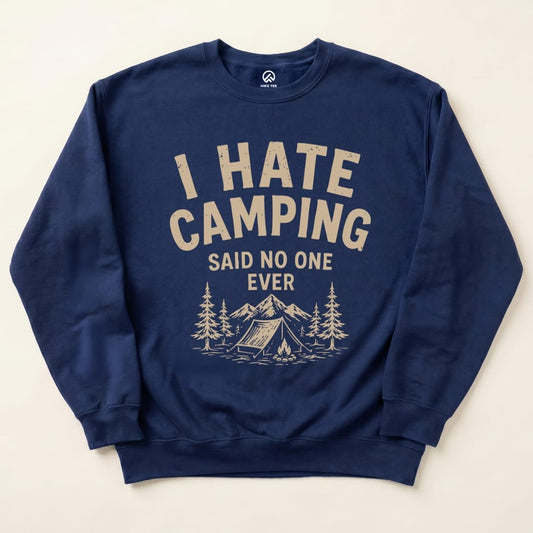 A navy graphic sweatshirt featuring the phrase "I Hate Camping" with trees, mountains, and a tent design below.