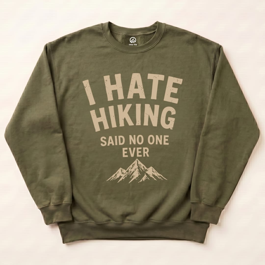 Olive green "I Hate Hiking Sweatshirt" featuring bold cream text and mountain graphic, displayed flat on a light background.