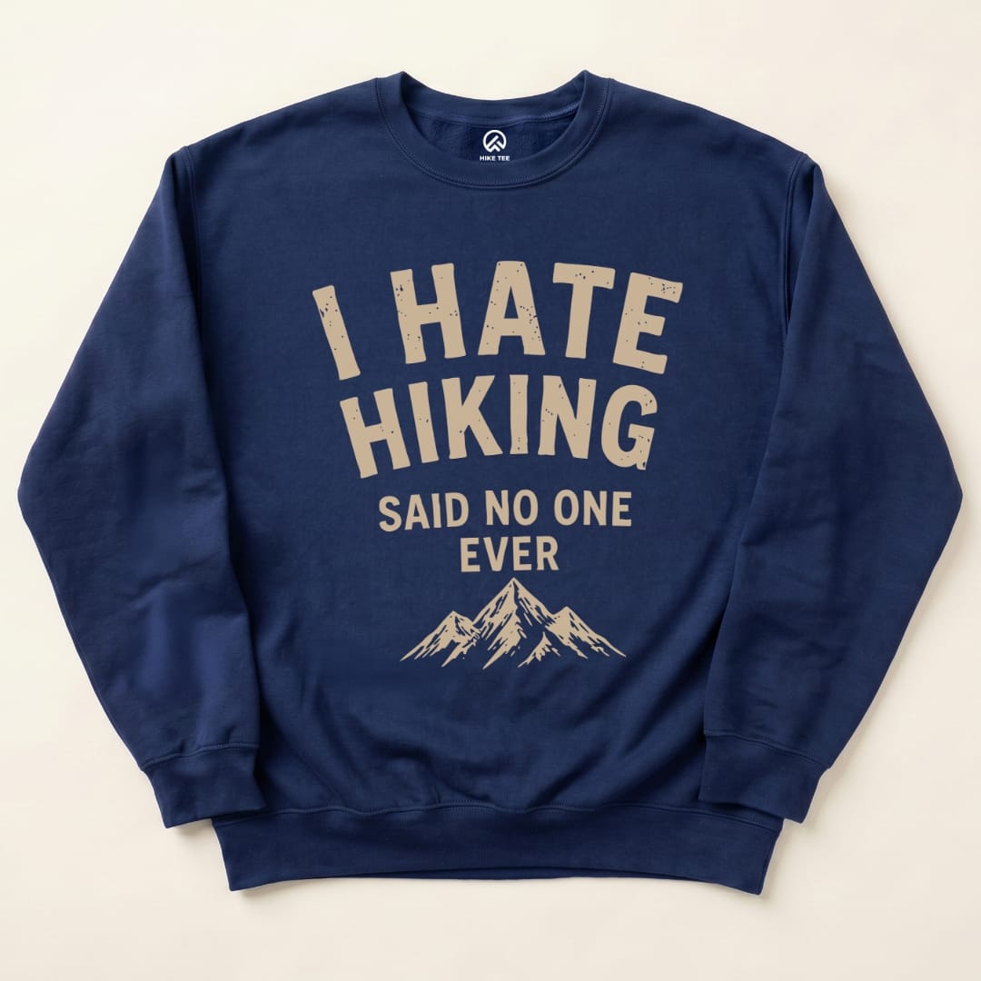 A navy "I Hate Hiking Sweatshirt" featuring a graphic with mountains and the phrase “I Hate Hiking Said No One Ever” printed in beige.