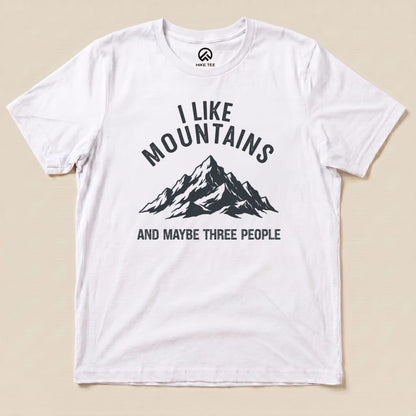 A white graphic t-shirt featuring a black mountain design and the text "I Like Mountains AND MAYBE THREE PEOPLE.