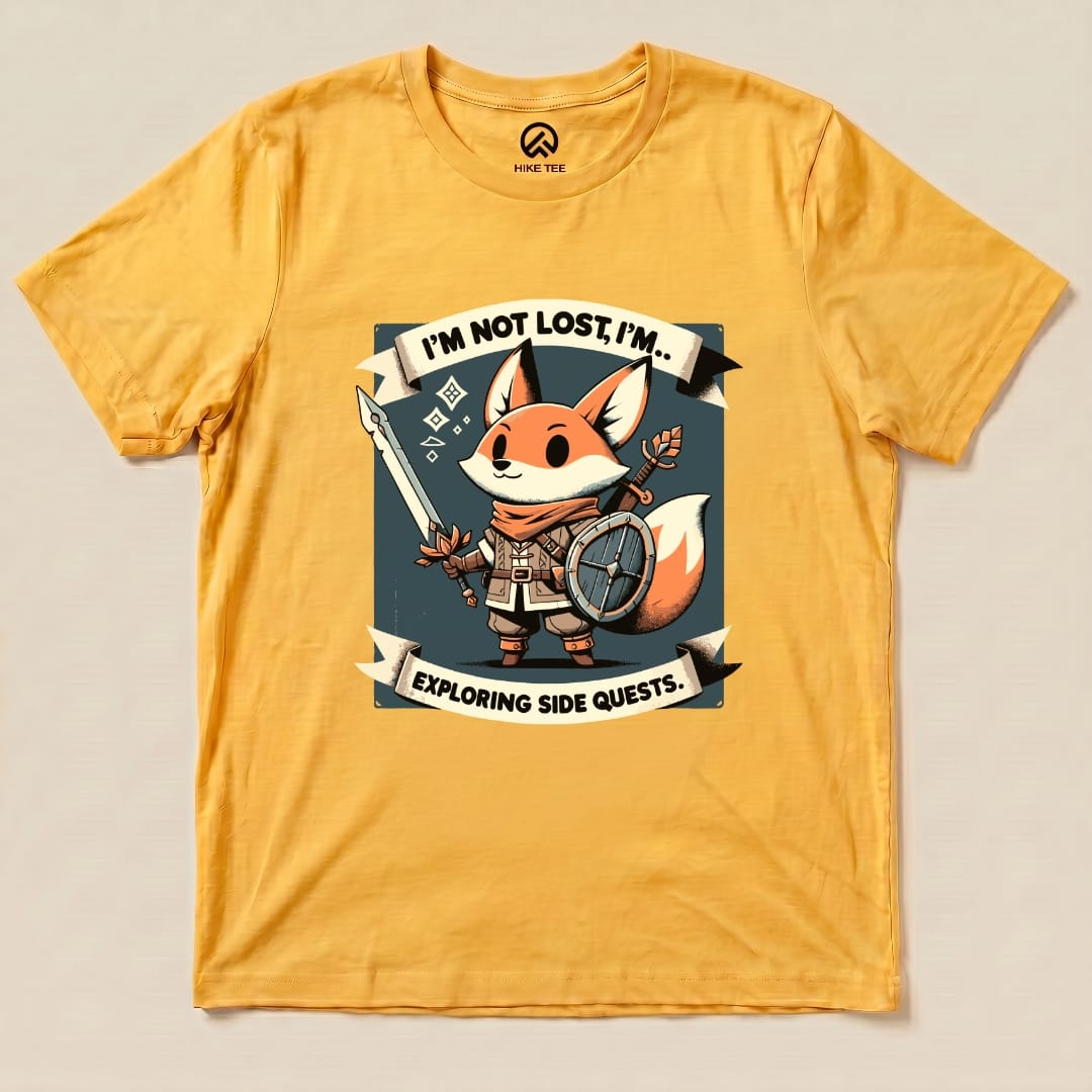 A graphic t-shirt in yellow featuring a fox character with a sword and shield, labeled "I'm Not Lost, I'm Exploring Side Quests.