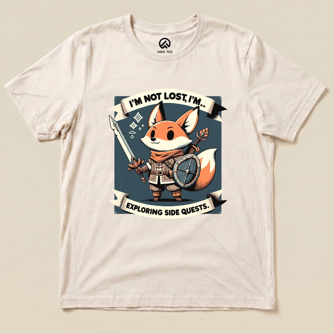 Graphic t-shirt featuring a cheerful fox character holding a sword and shield, with the slogan "I'm Not Lost, I'm... Exploring Side Quests.