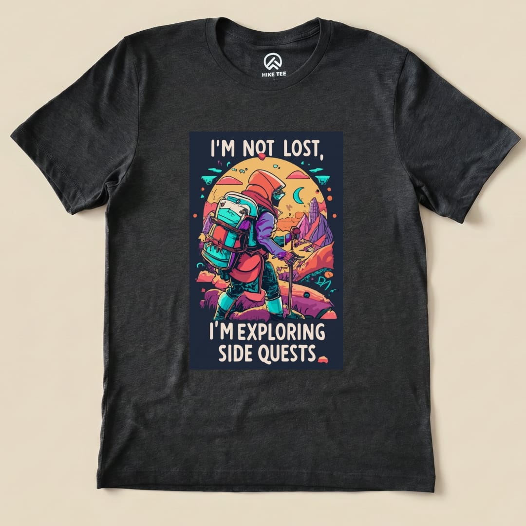 A black graphic t-shirt features the phrase "I'M NOT LOST, I'M EXPLORING SIDE QUESTS" alongside a backpacker exploring a vibrant landscape.