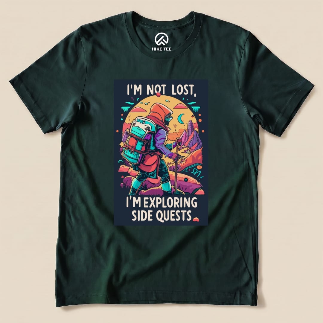 A graphic t-shirt featuring the slogan "I'm Not Lost, I'm Exploring Side Quests" with a colorful hiker in a scenic outdoor setting.
