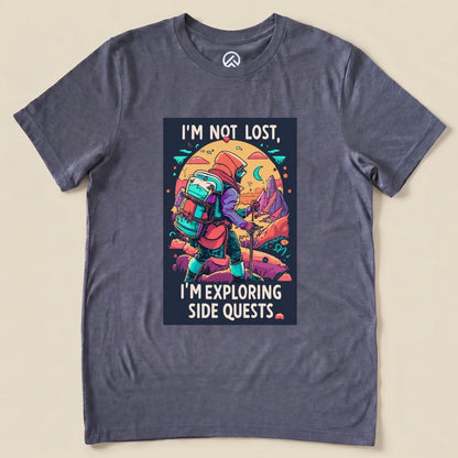 A graphic t-shirt featuring the phrase "I'm Not Lost, I'm Exploring Side Quests" alongside an illustrated hiker with a backpack.