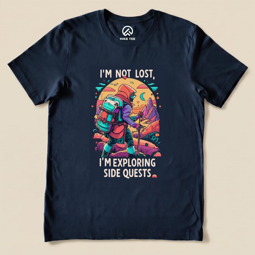 A navy graphic t-shirt features a colorful illustration of a hiker with the text "I'm Not Lost, I'm Exploring Side Quests.