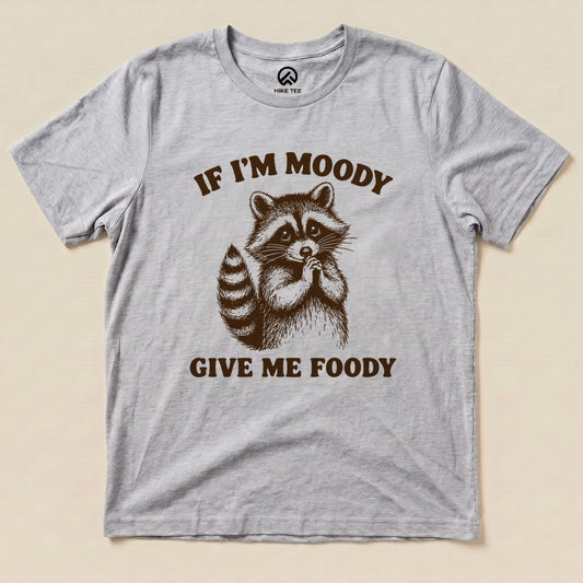 A gray graphic t-shirt features an illustration of a raccoon with the text "IF I'M MOODY GIVE ME FOODY" below it.