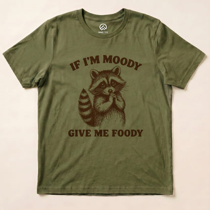 A graphic t-shirt in olive green featuring a raccoon and the text "IF I'M MOODY GIVE ME FOODY" in bold letters.