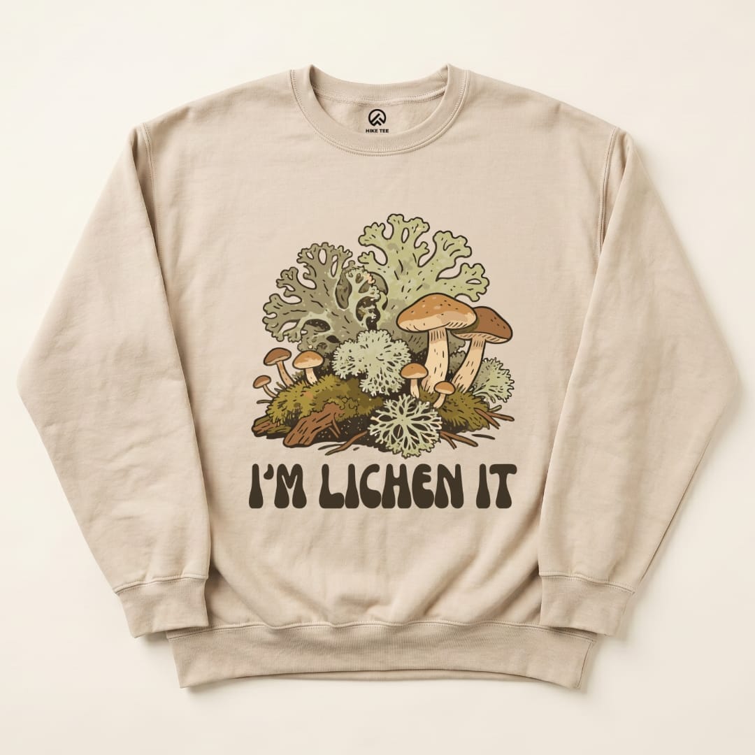A beige sweatshirt featuring the graphic "I'm Lichen It" with colorful mushrooms and lichen designs on the front.