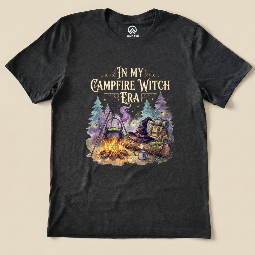 Dark Grey Heather In My Campfire Witch Era Shirt with a witch cauldron over a campfire with a witch hat and backpack graphic