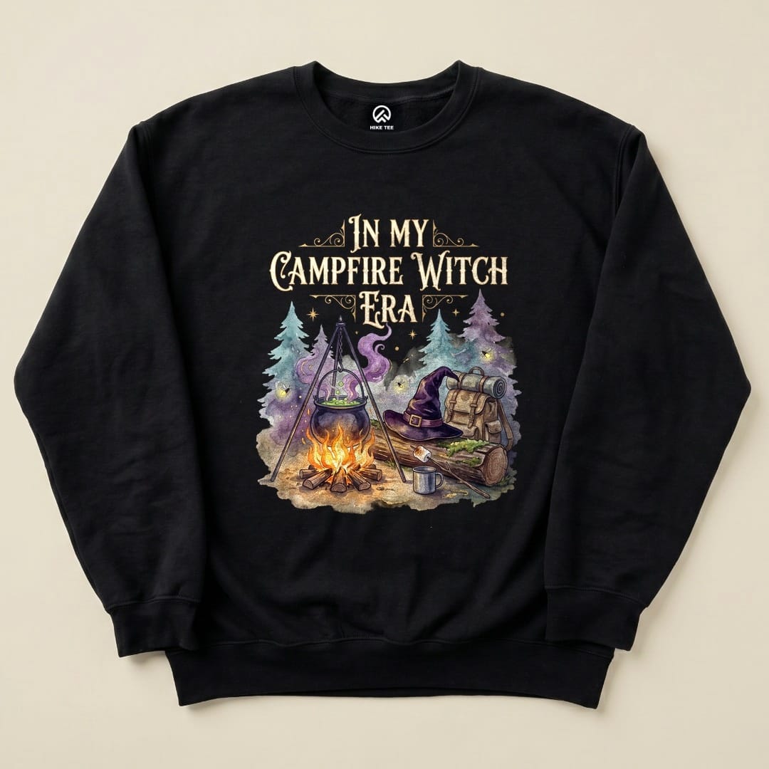 The "In My Campfire Witch Era Sweatshirt" features a whimsical graphic of a campfire scene with a cauldron, backpack, and witch's hat.