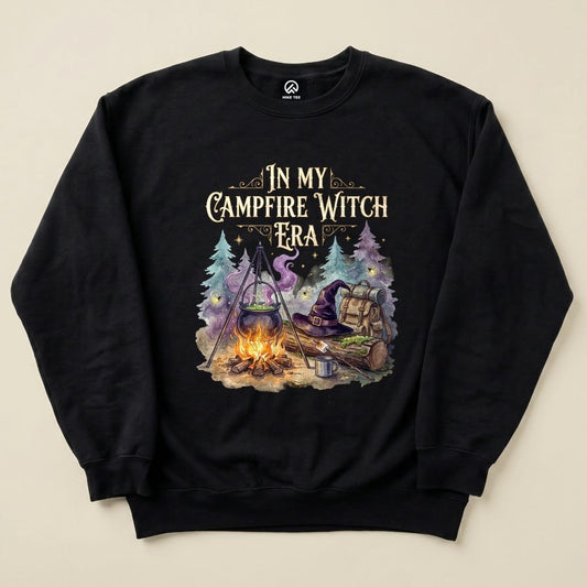 The "In My Campfire Witch Era Sweatshirt" features a whimsical graphic of a campfire scene with a cauldron, backpack, and witch's hat.