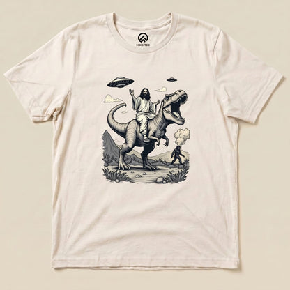 A graphic t-shirt featuring Jesus riding a T-rex with Bigfoot in the background and UFOs in the sky, titled "Jesus with T-rex and Bigfoot Shirt.
