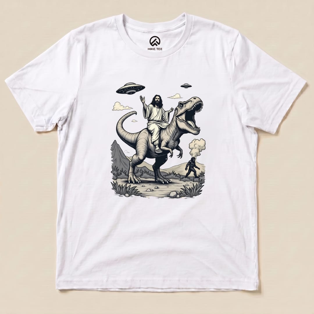 A graphic t-shirt features a whimsical design of Jesus riding a T-rex, with Bigfoot in the background and UFOs above.