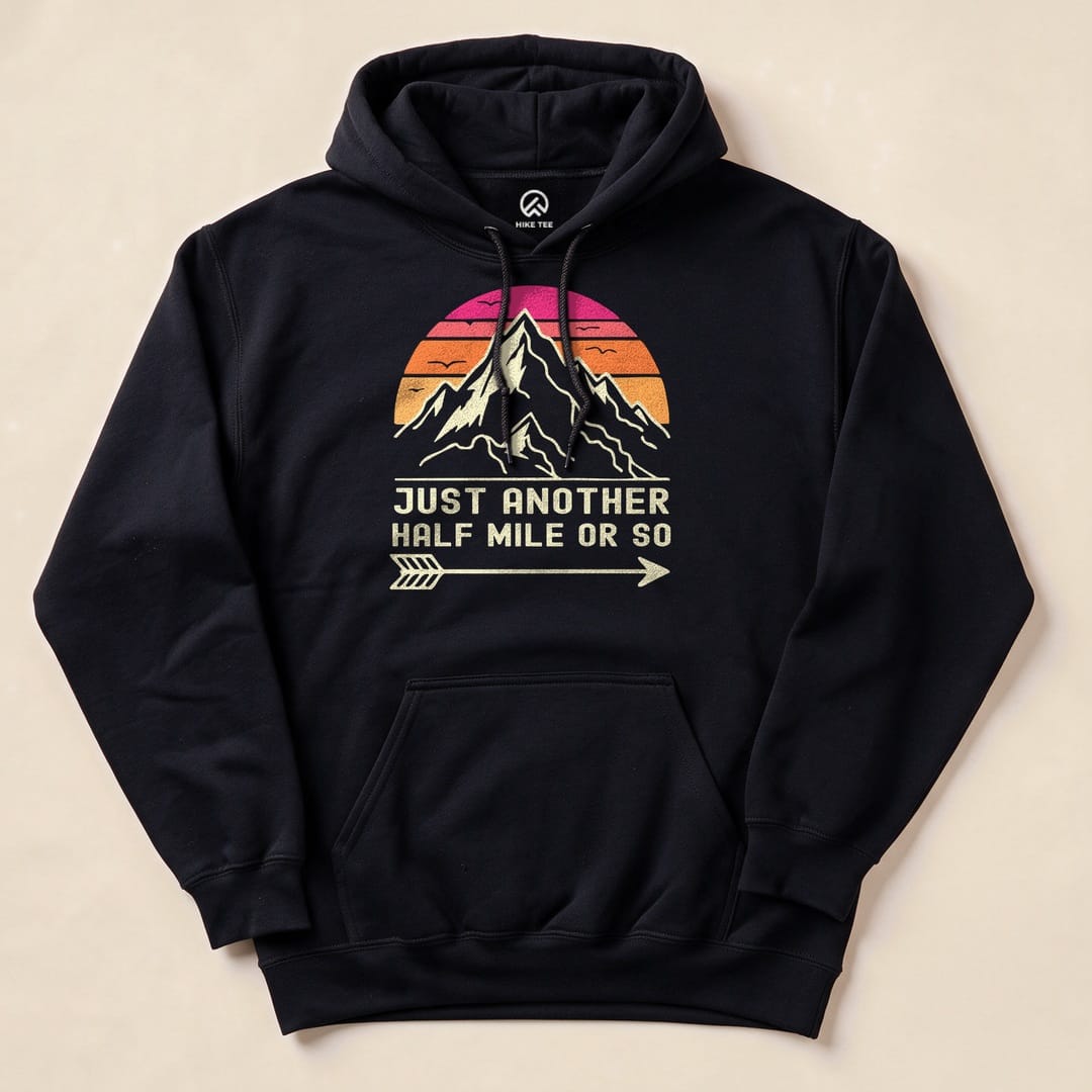 A black hoodie featuring a mountain graphic and the slogan "Just Another Half Mile or So" printed in vibrant colors.